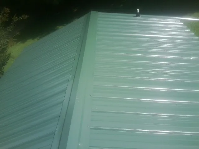 New green metal panels meeting at the ridge of a roof — Flat Roof Repair work by our crew in Marsteller
