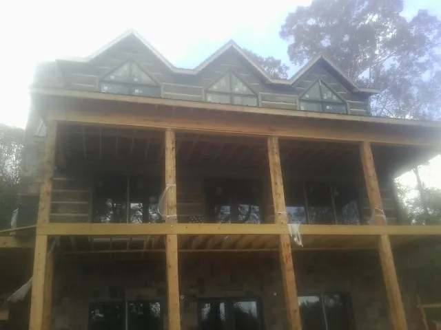 Dormers and porch framing on a large log home under construction — Roof Coating work by our crew in Marsteller
