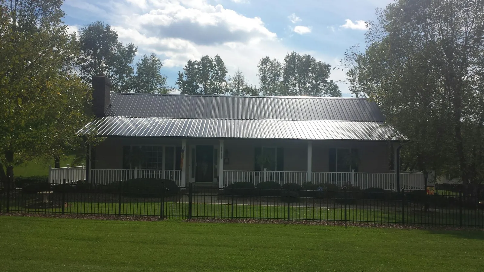 Gray metal roof on a brick ranch with a full width front porch — Gutter Guard Installation work by our crew in Marsteller