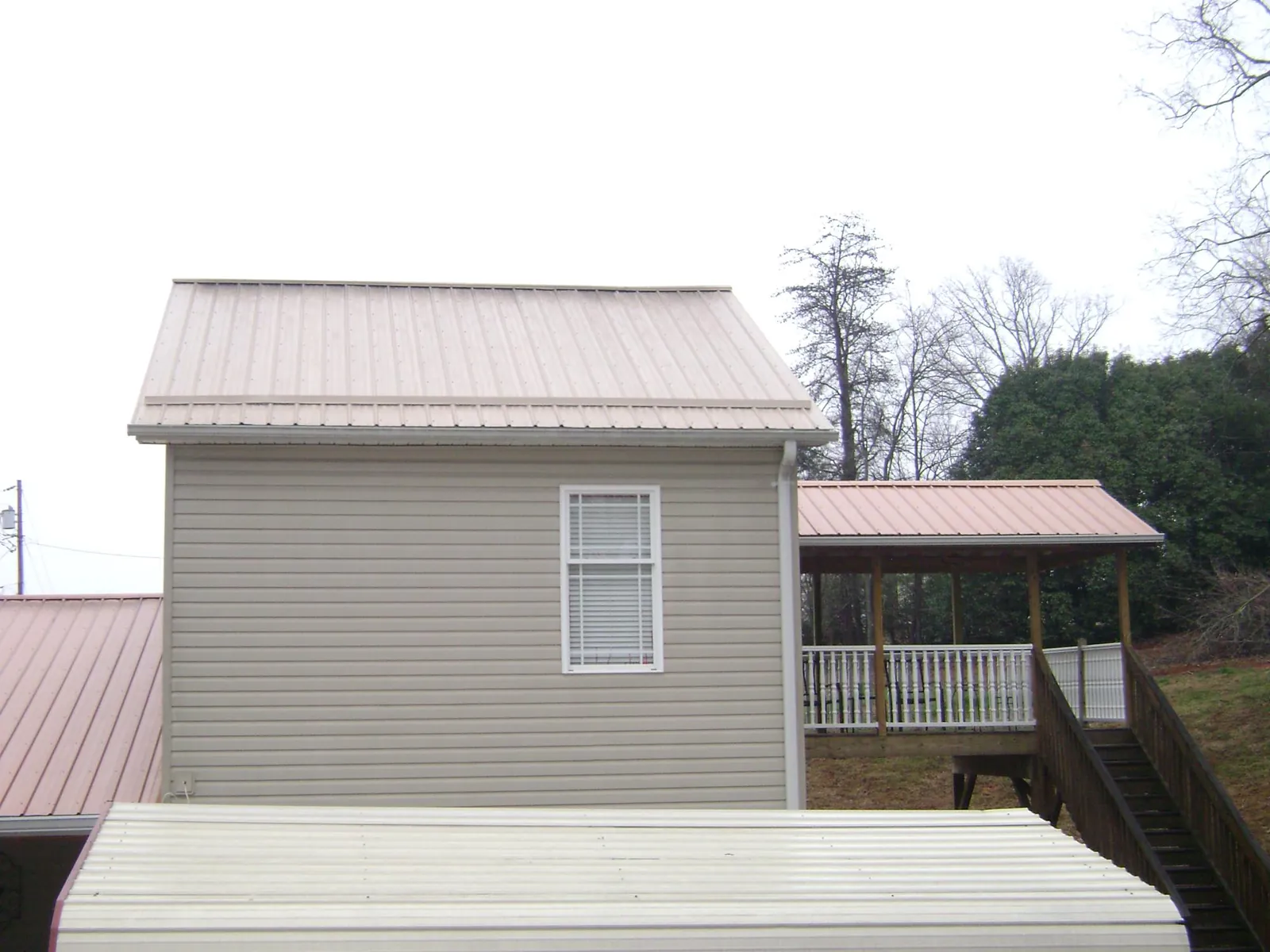 Tan metal roofs on a two story addition and attached porch, from a Roof Replacement job in Marsteller
