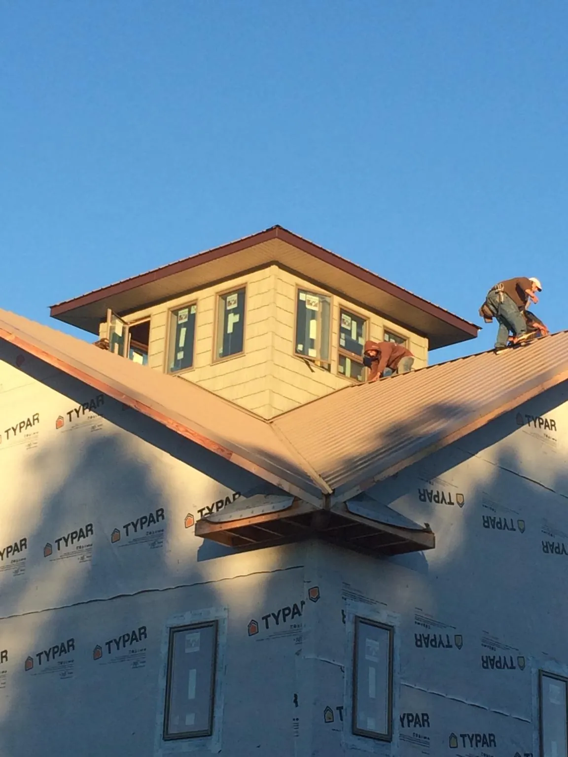 Roofers working around a rooftop cupola on a new metal roof at sunset — Roof Waterproofing in Marsteller by Roofing Brothers